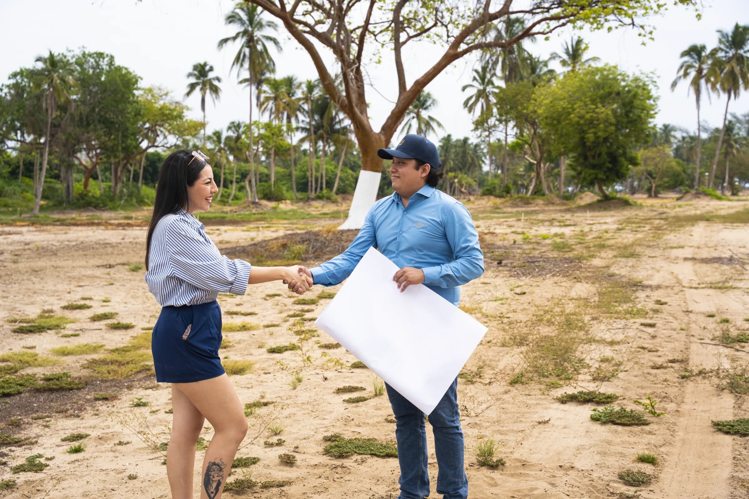 Asesor y cliente cerrando un acuerdo con el plano de distribución de Altamar en el terreno