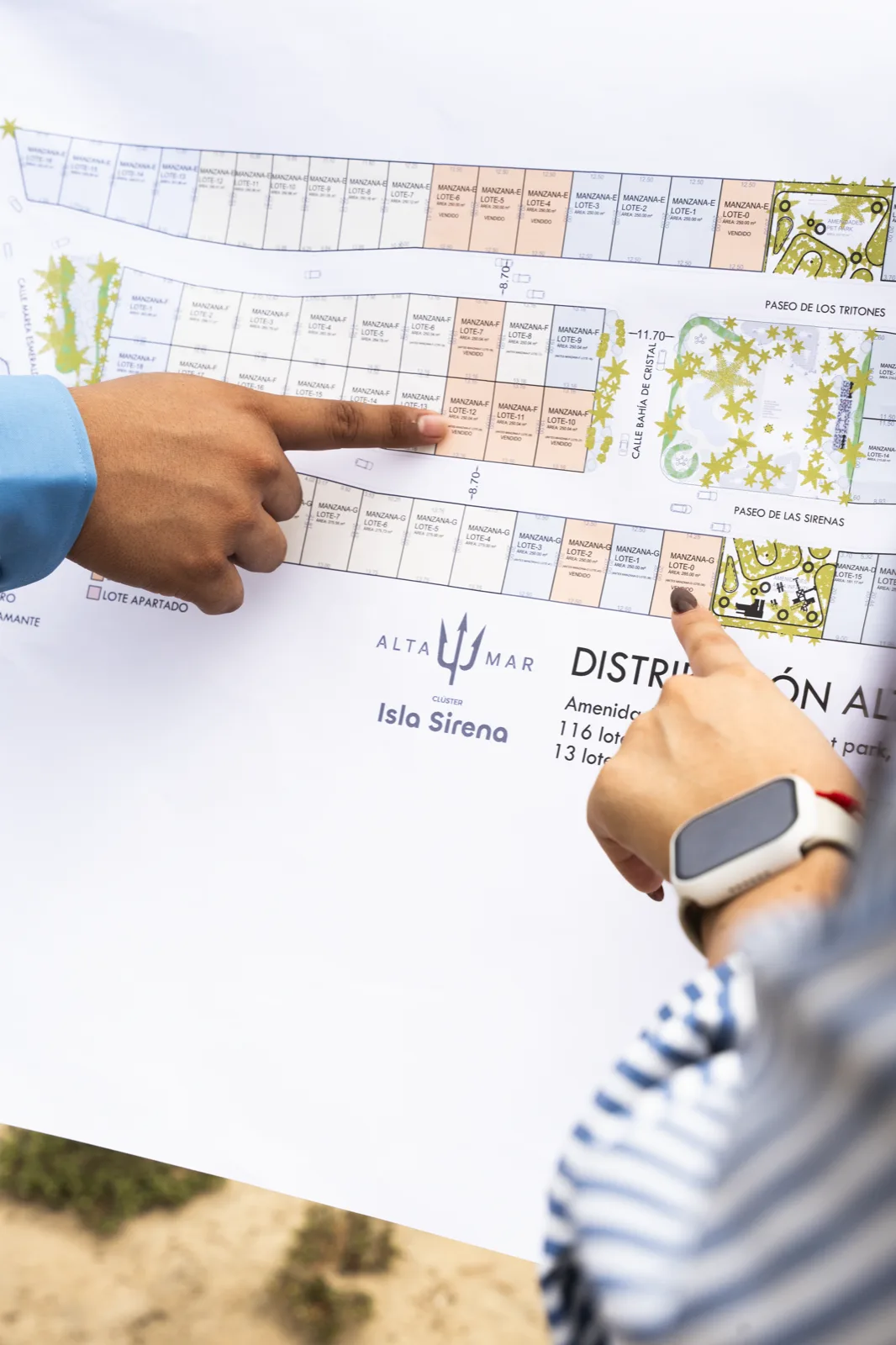 Manos señalando el plano oficial impreso de distribución de lotes de Altamar, clúster Isla Sirena